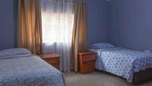 Ein Schlafzimmer mit zwei Betten, einem Nachttisch und einem Fenster mit Vorhängen.