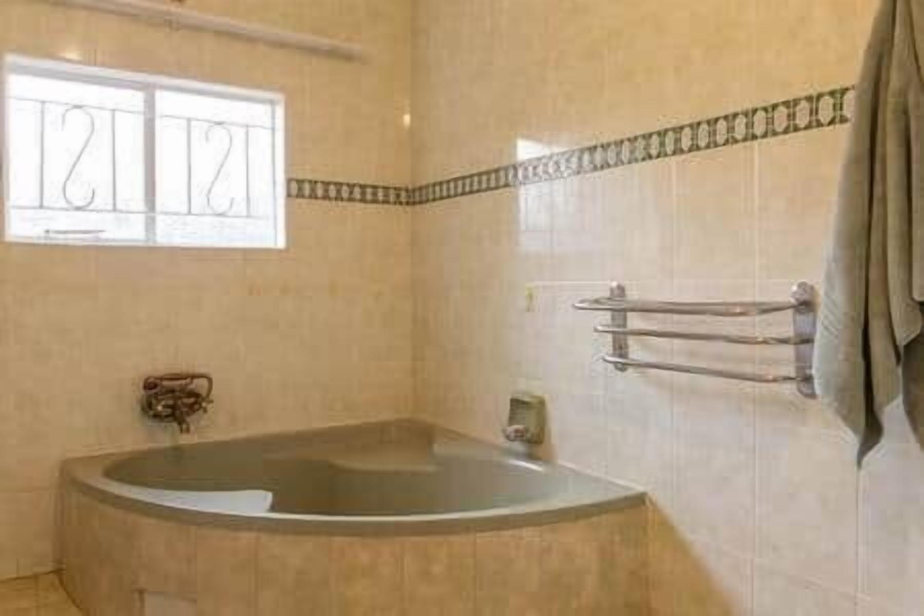 A bathroom with a bathtub, a towel rack, and a window with a view.