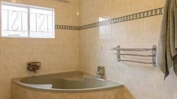 A bathroom with a bathtub, a towel rack, and a window with a view.