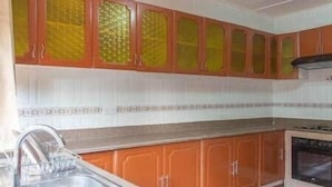 Eine Küche mit orangenen Schränken, einer Edelstahl-Spüle und einem Herd.