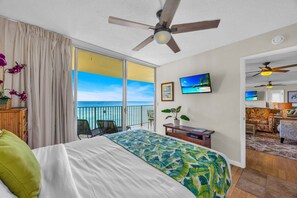 A hotel room with a bed, a desk, a chair, a TV, and a balcony with a view of the ocean. - Island Style OceanFront 2BD Wonderful Views -Hololani A701 (Lahaina)