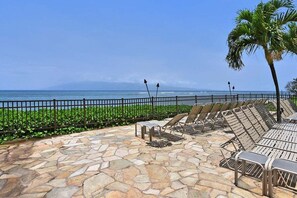 Un patio de piedra con sillones de descanso y vista al océano.