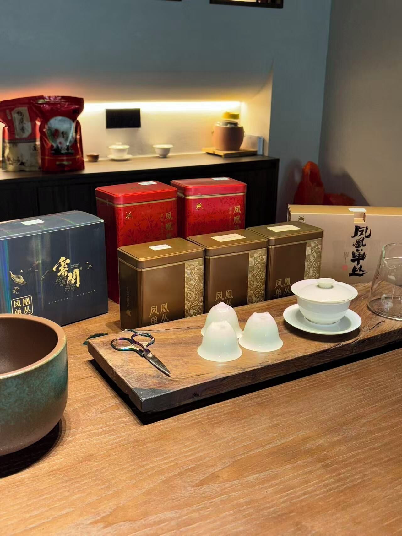 Una mesa de madera con vajilla de té, incluyendo teteras y tazas, y un par de tijeras.