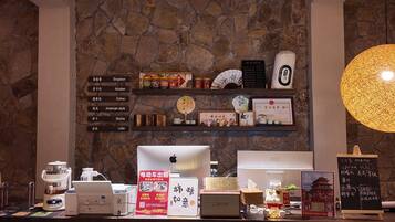 Un caffè con parete in pietra, scaffali con chicchi di caffè, un MacBook, una macchina da caffè e una lavagna con il menu.