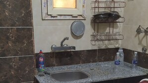 A kitchen with a gas stove, sink, and tiled backsplash.