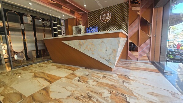A hotel reception desk with a marble floor, a modern design, and a sign that reads "HOTEL PINAKI". - Hotel Pinaki (Ajmer)