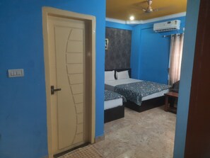 Une pièce avec une porte, deux lits, un ventilateur de plafond et un appareil de climatisation.