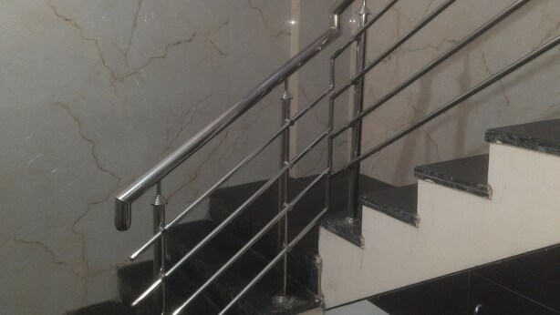 A staircase with a metal handrail and marble walls. - Hotel Royal Comfort (Bengaluru)