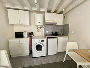 Une petite cuisine équipée d’un four à micro-ondes, d’un lave-linge et d’un petit évier.
