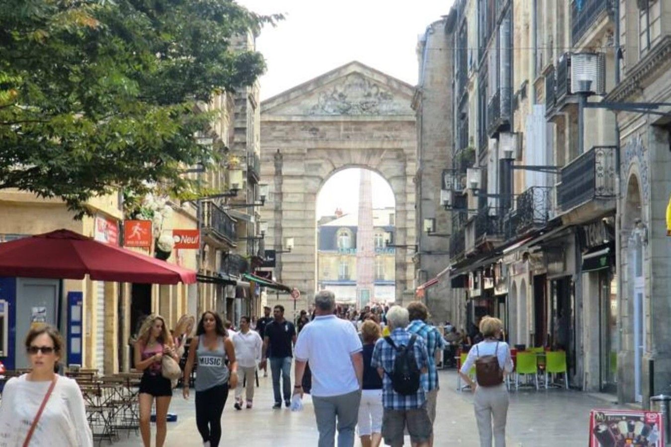 Una calle peatonal con arquitectura histórica, que incluye un arco, y gente caminando.
