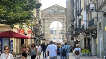 Una calle peatonal con arquitectura histórica, que incluye un arco, y gente caminando.