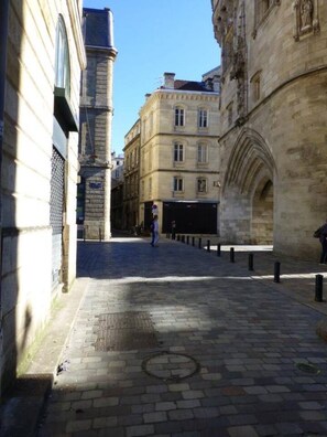 Eine Kopfsteinpflasterstraße mit historischen Gebäuden, blauem Himmel und einer Person, die unterwegs ist.