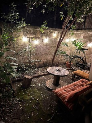 An outdoor seating area with a round table and a bench, surrounded by plants and a brick wall. - Very nice apartment with garden (Bordeaux)