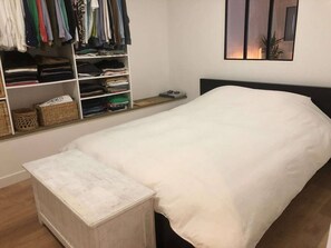 A neatly organized bedroom with a single bed, a bedside table, and a wardrobe with folded clothes. - Very nice apartment with garden (Bordeaux)
