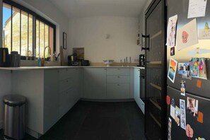 Eine Küche mit einer gewölbten Arbeitsplatte, einem Kühlschrank mit Fotos und einem Fenster, das für natürliches Licht sorgt.