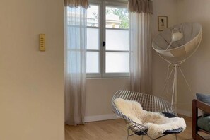 Une pièce avec une grande fenêtre, un fauteuil doté d’un coussin moelleux et une antenne parabolique.