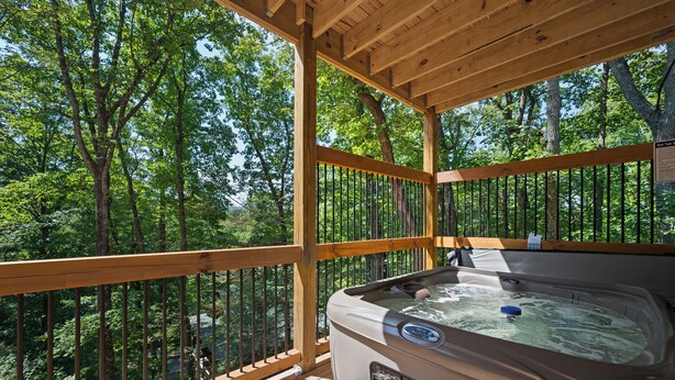 Un jacuzzi en una terraza de madera con vistas a un bosque.