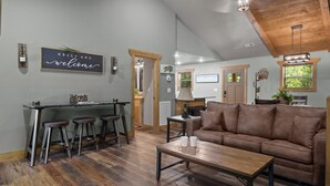 Un interior moderno con área de cocina, taburetes de bar, un sofá marrón y una mesa de centro de madera.