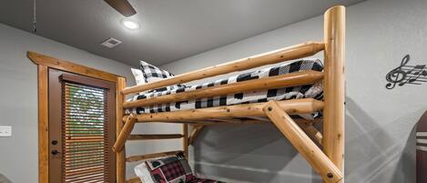 A bunk bed with a checkered blanket, a wooden door with blinds, and a wall with a musical note design.