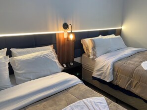 A hotel room with two beds, a nightstand, a wall-mounted lamp, and a headboard.