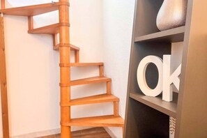 A wooden spiral staircase with a black shelf beside it. - Charming Bordeaux Apartment: Heart of the City (Bordeaux)