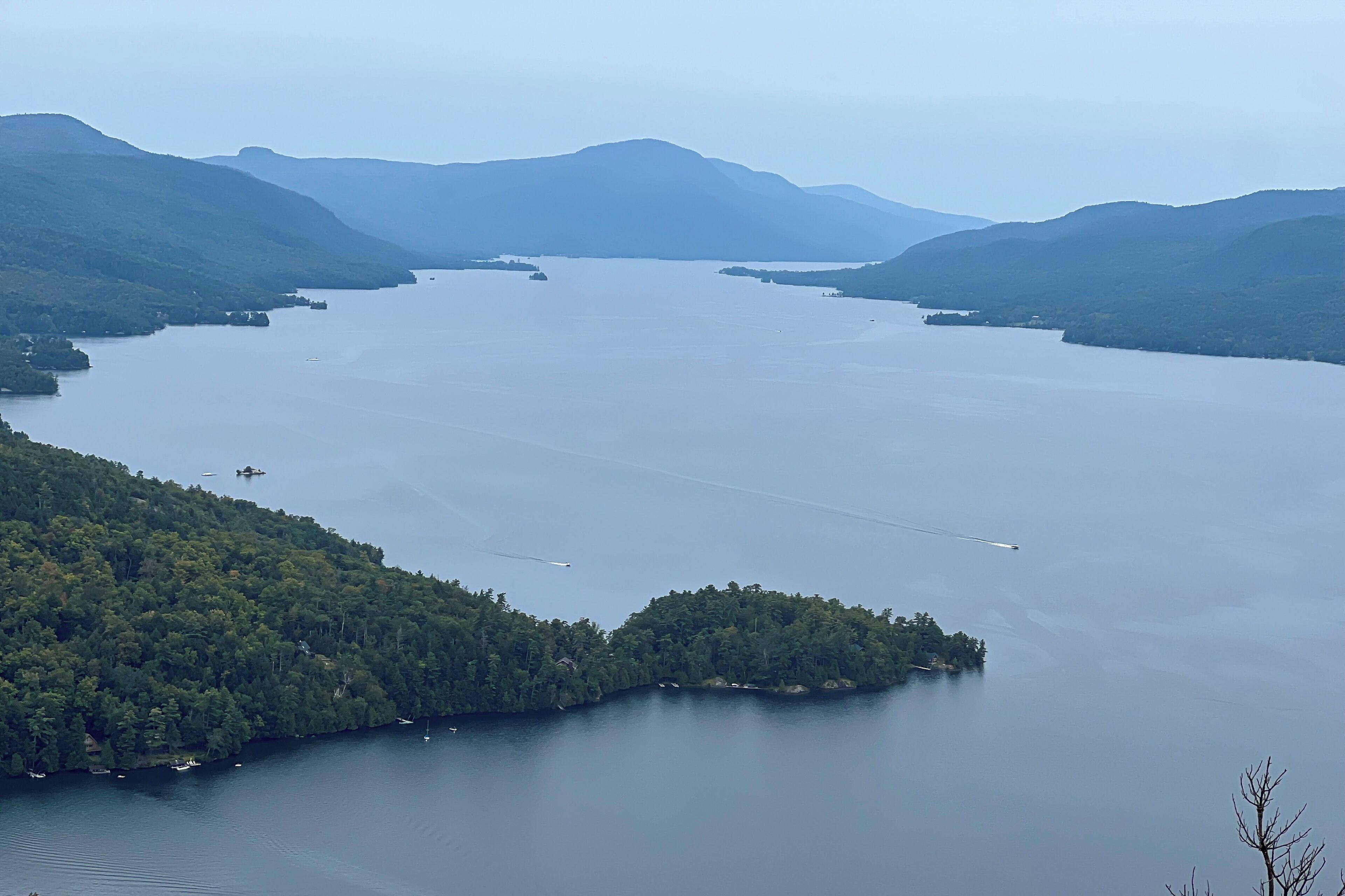 Une vaste étendue d’eau entourée de collines boisées.