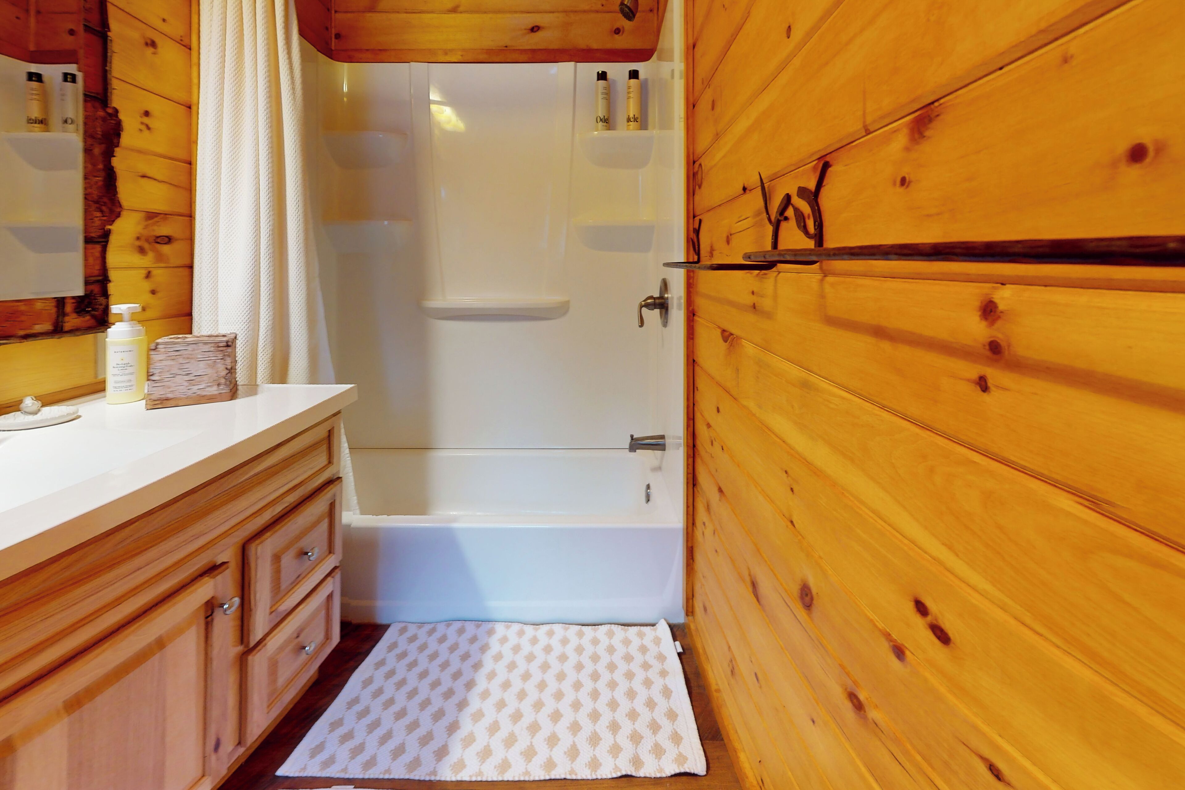A wooden cabin bathroom with a bathtub, wooden cabinets, and a towel rack.