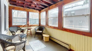 Un solárium con ventanas amplias, mobiliario de mimbre y techo de madera.