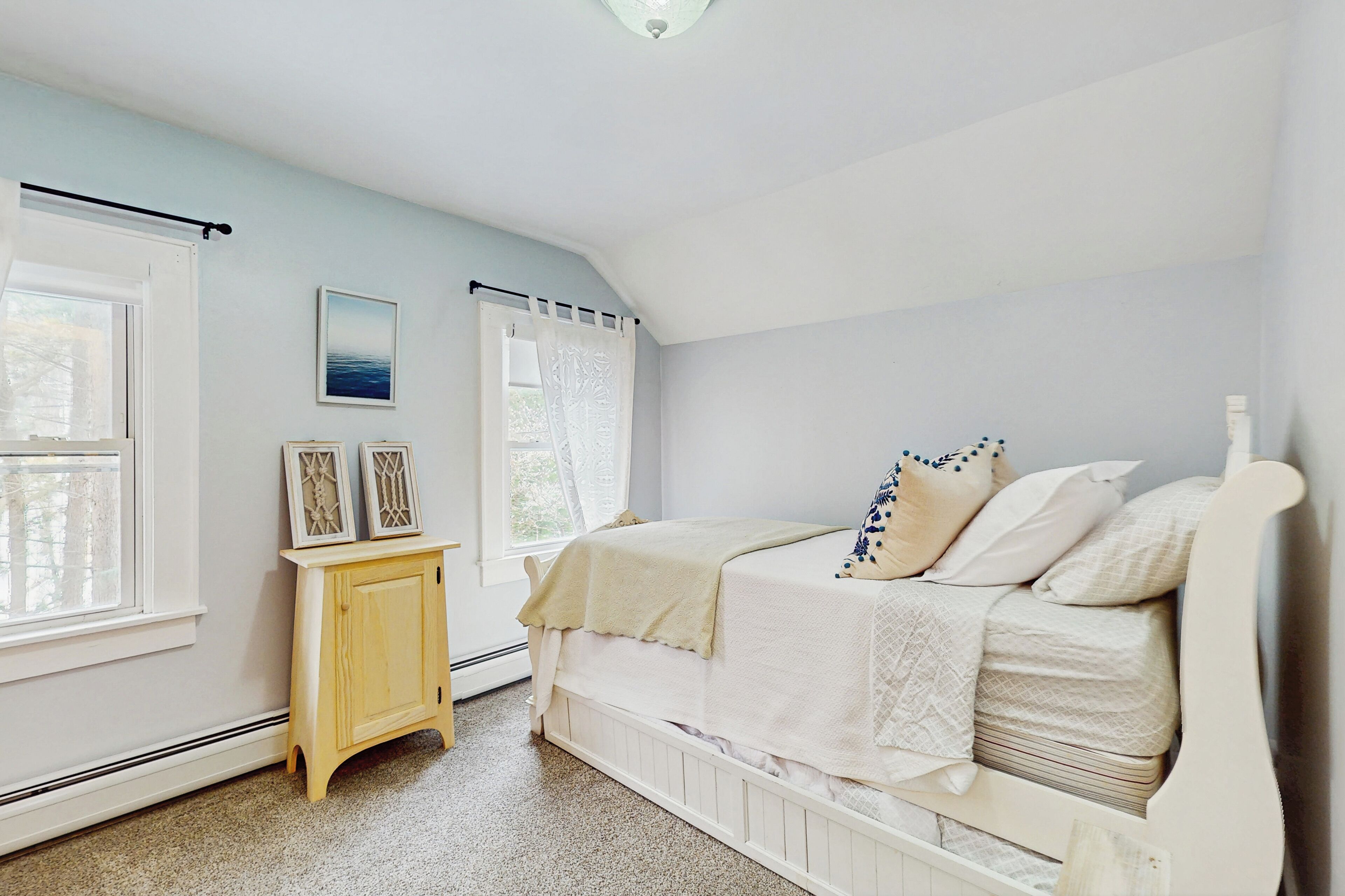 A bedroom with a bed, a nightstand, and a window.