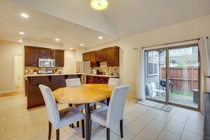 A spacious kitchen with a dining area, featuring a large island, modern appliances, and a sliding glass door to the backyard.