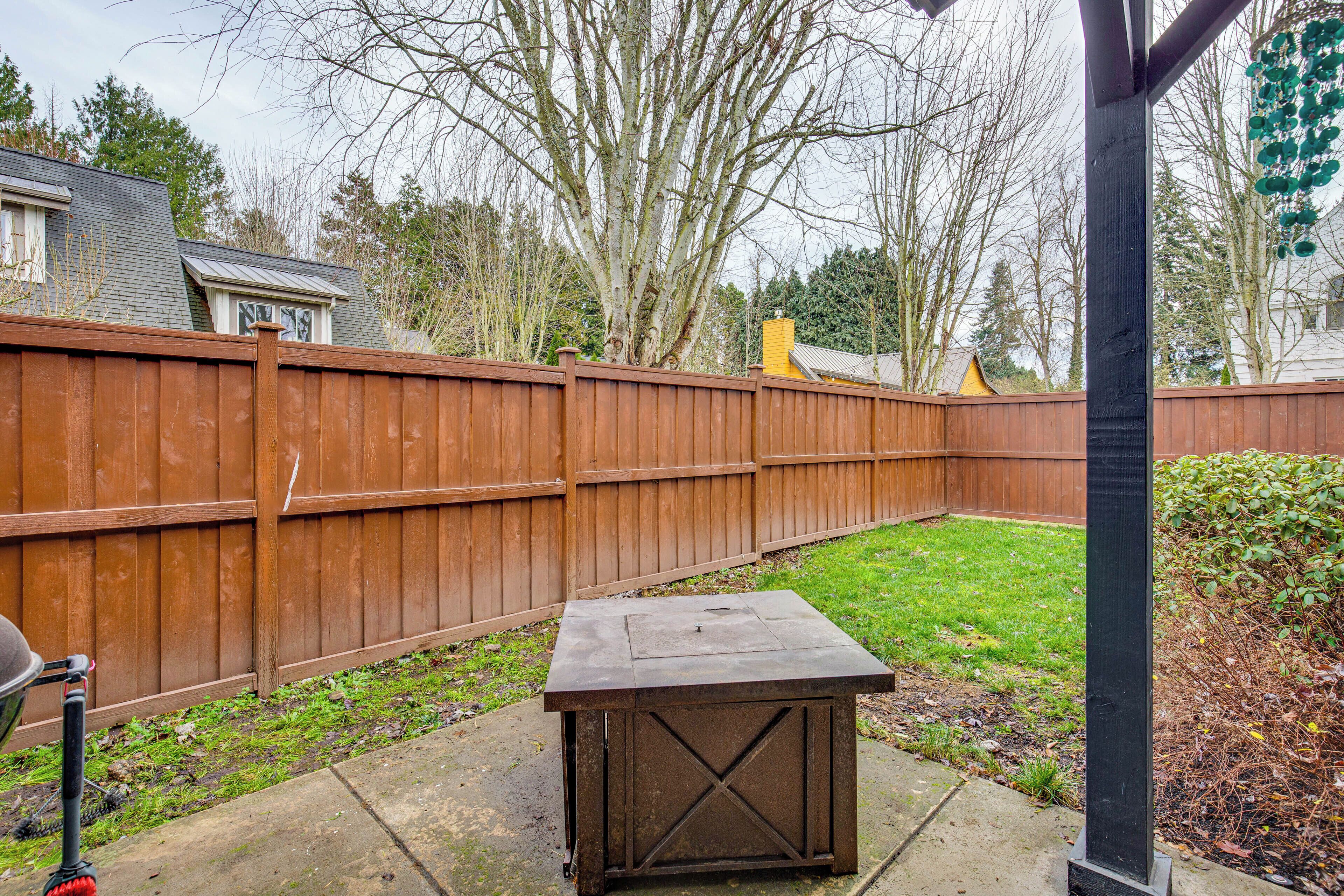 A backyard with a wooden fence, a concrete patio, and a metal shed.