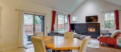 A spacious living area with a fireplace, a dining table with chairs, and a sofa.