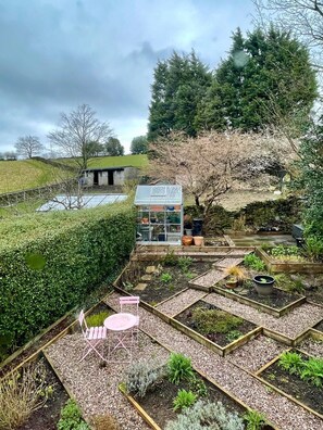 A garden with raised beds, a small structure, and a chair. - Panoramic Peak Views 3 Bed Log Fire Hill Walks (Glossop)