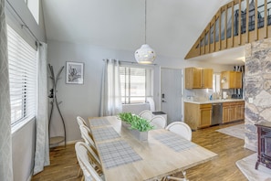 A dining area with a wooden table, white chairs, and a hanging light fixture. - Forest-front Munds Park Cabin w/ ATV Access (Munds Park)
