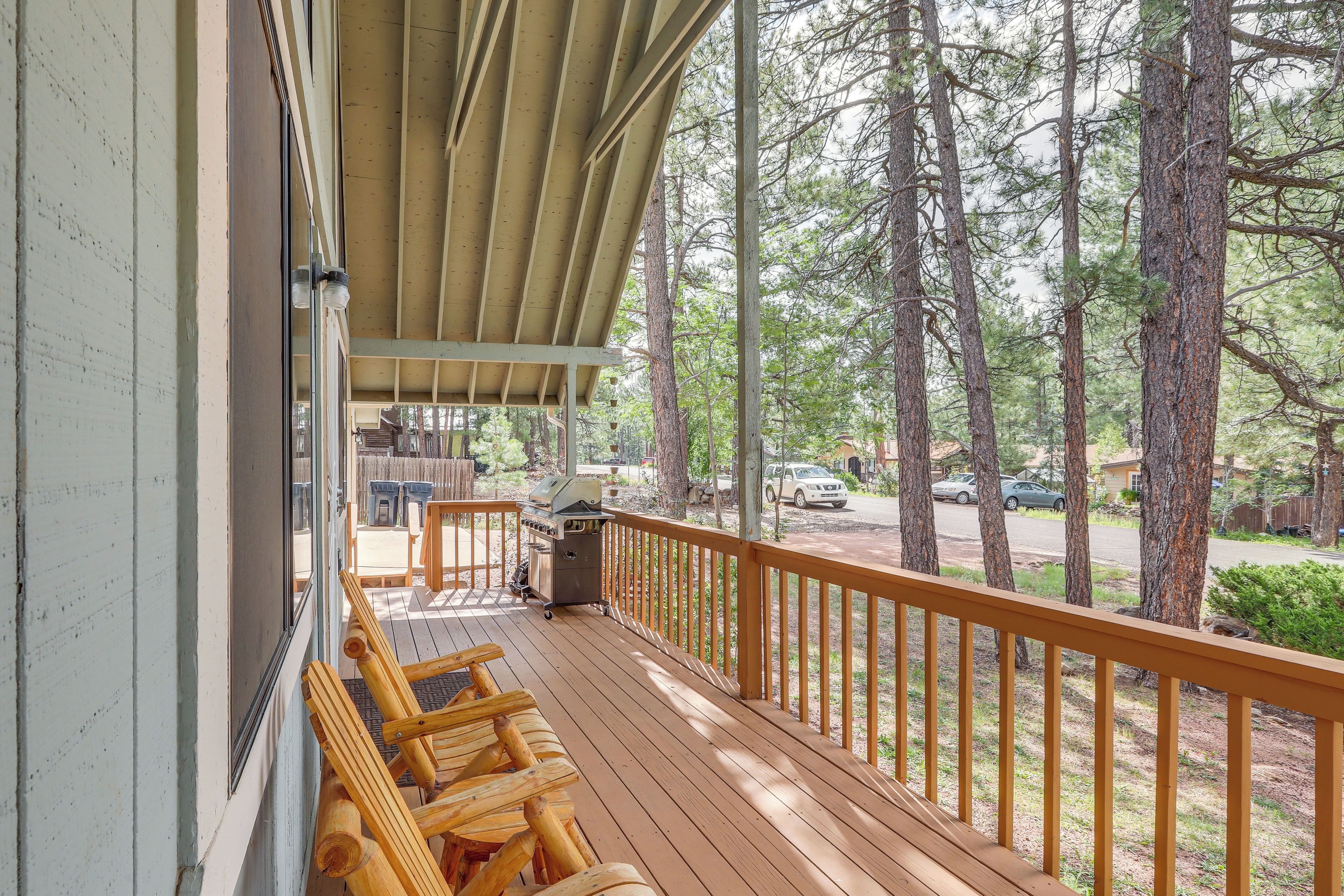 A wooden deck with a railing, a grill, and outdoor seating.