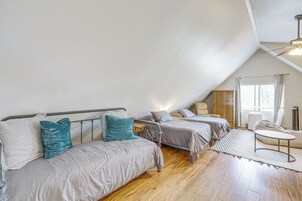 Habitación con dos camas, piso de madera, ventilador de techo y ventana con cortinas.