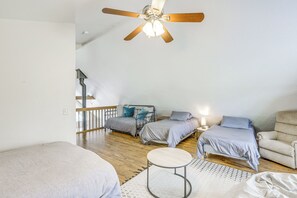 Un dormitorio con dos camas, un ventilador de techo, una mesita redonda y una silla.