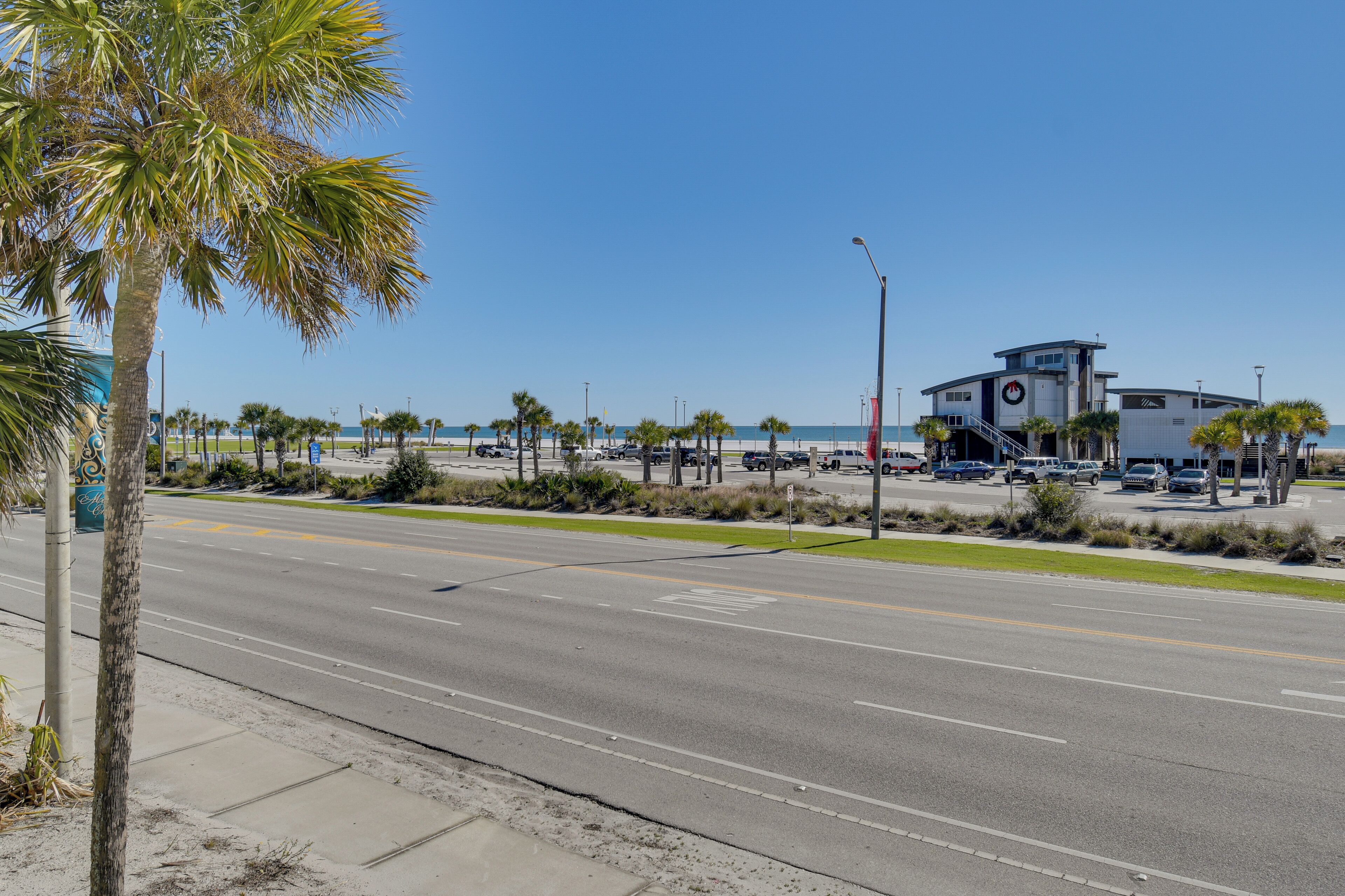 A coastal road with a lifeguard tower, palm trees, and a beach in the background.