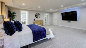 A bedroom with a bed, a TV mounted on the wall, and a door leading to another room. - 1 Mile to Quantico: 5BR Home w/ Game Room! (Triangle)