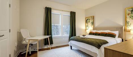 A bedroom with a bed, a desk, a chair, and a window with curtains.
