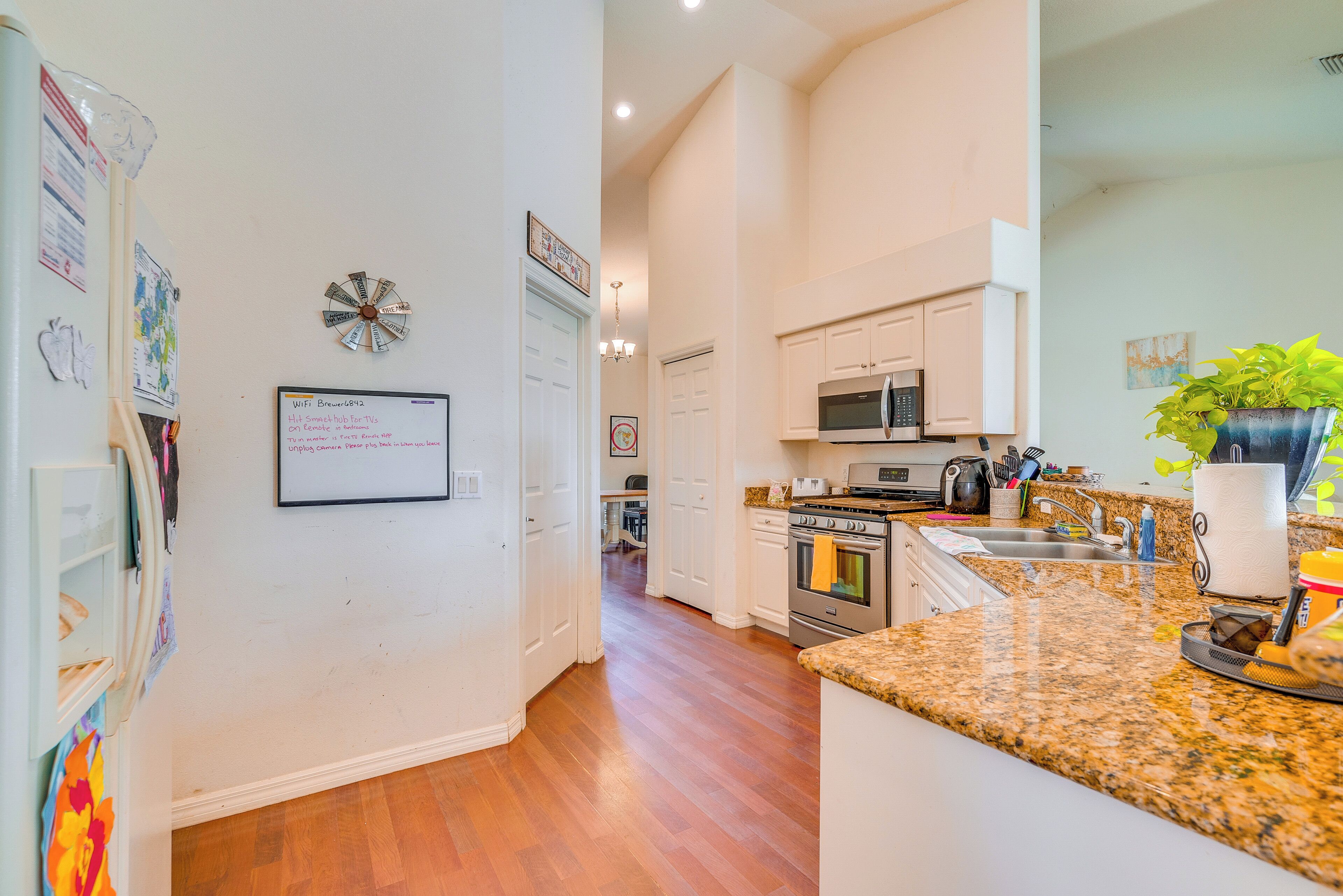 A kitchen with white cabinets, a granite countertop, a microwave, and an oven.