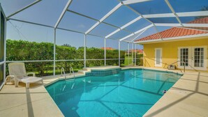 Una piscina cubierta con agua azul cristalina, una silla blanca y un edificio amarillo al fondo.