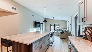 A modern kitchen with a large island, built-in appliances, and a dining area with a sofa and bar stools. - 1 Mi to Beach! Modern Tropical Retreat in Naples (Naples)