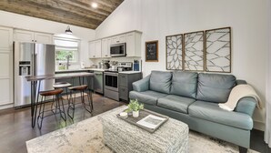 A modern kitchen with white cabinets, stainless steel appliances, and a bar area. - Whitewood w/ Hot Tub: Peaceful Wildwood Retreat (Wildwood)