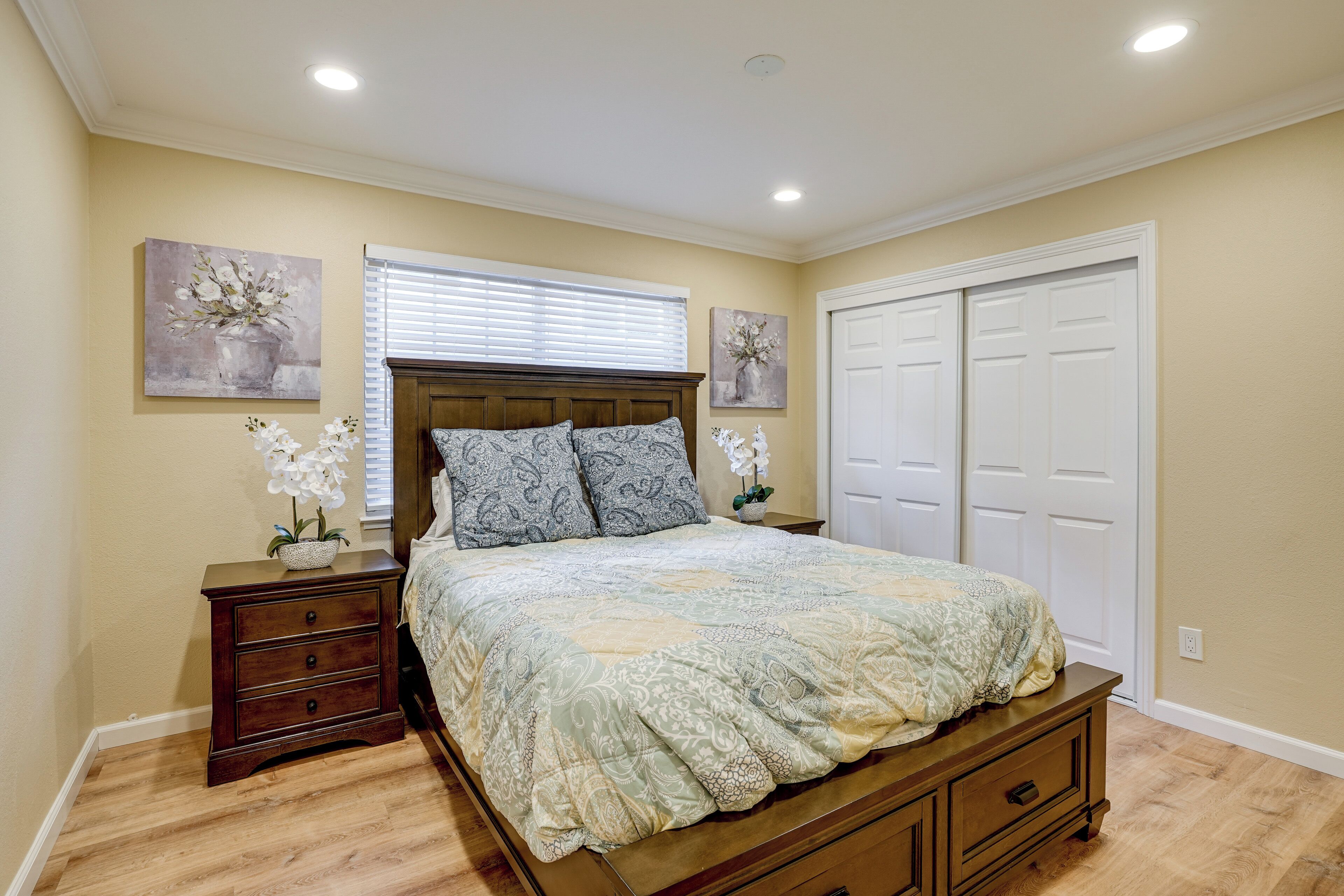 A bedroom with a bed, nightstands, a dresser, a window with blinds, and a closet.