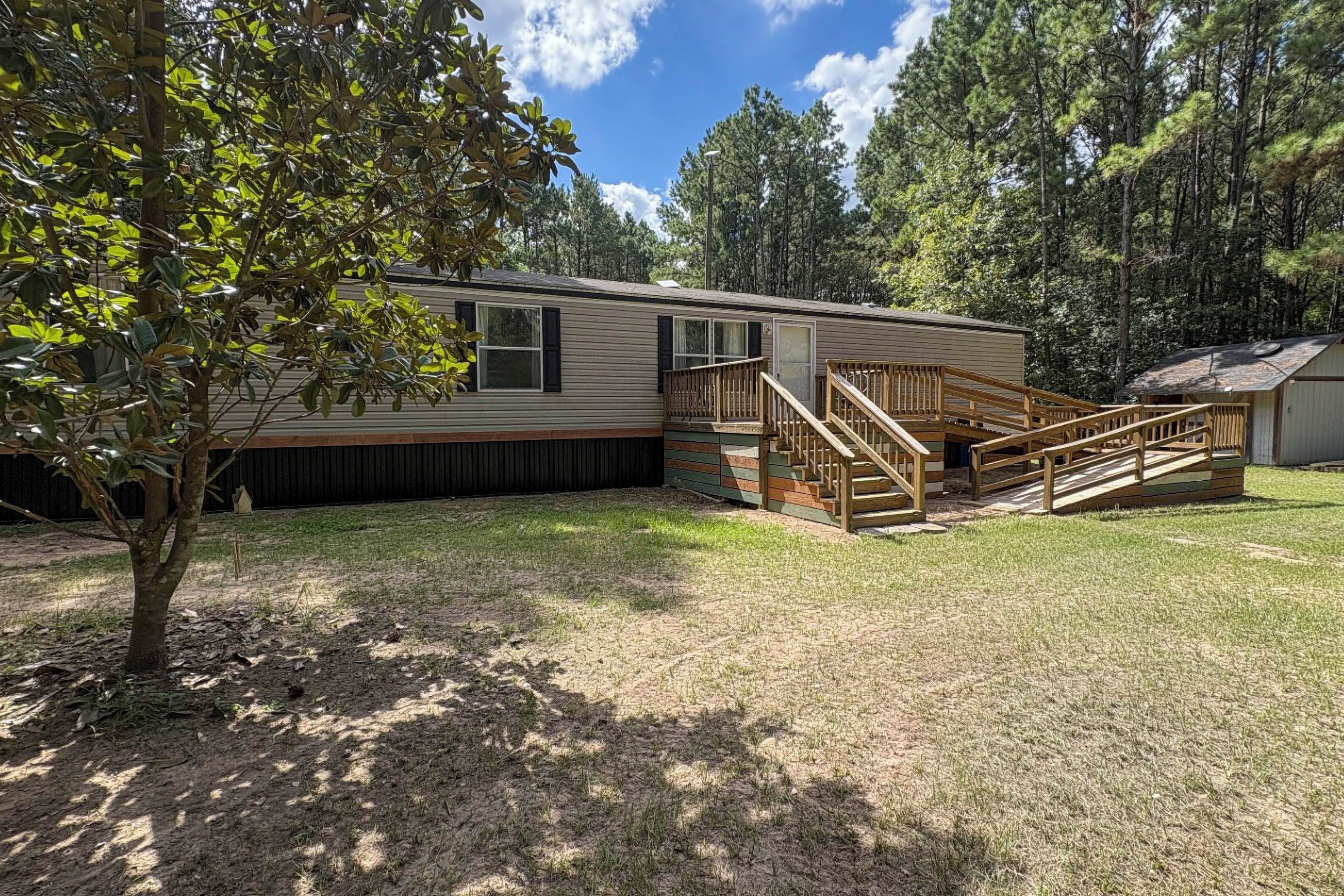 A single-story mobile home with a front porch and a small deck.