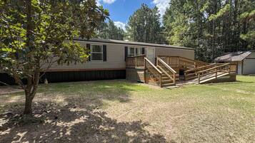 A single-story mobile home with a front porch and a small deck.