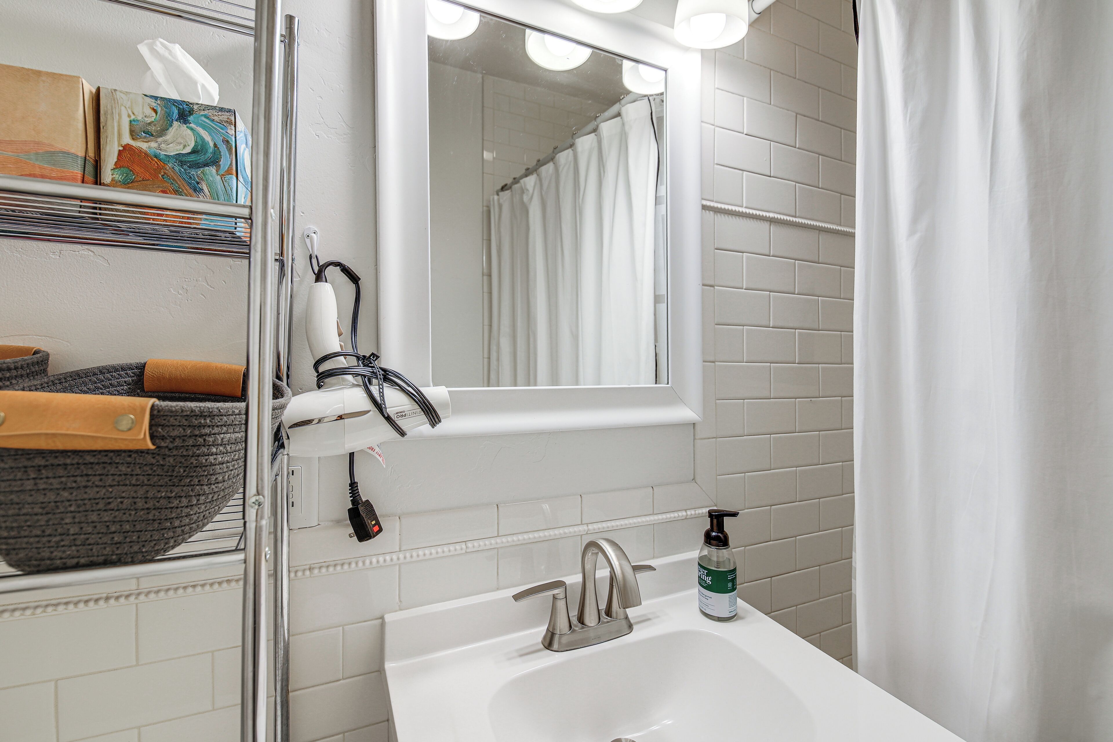A bathroom with a white sink, a mirror, a towel rack, and a shower curtain.
