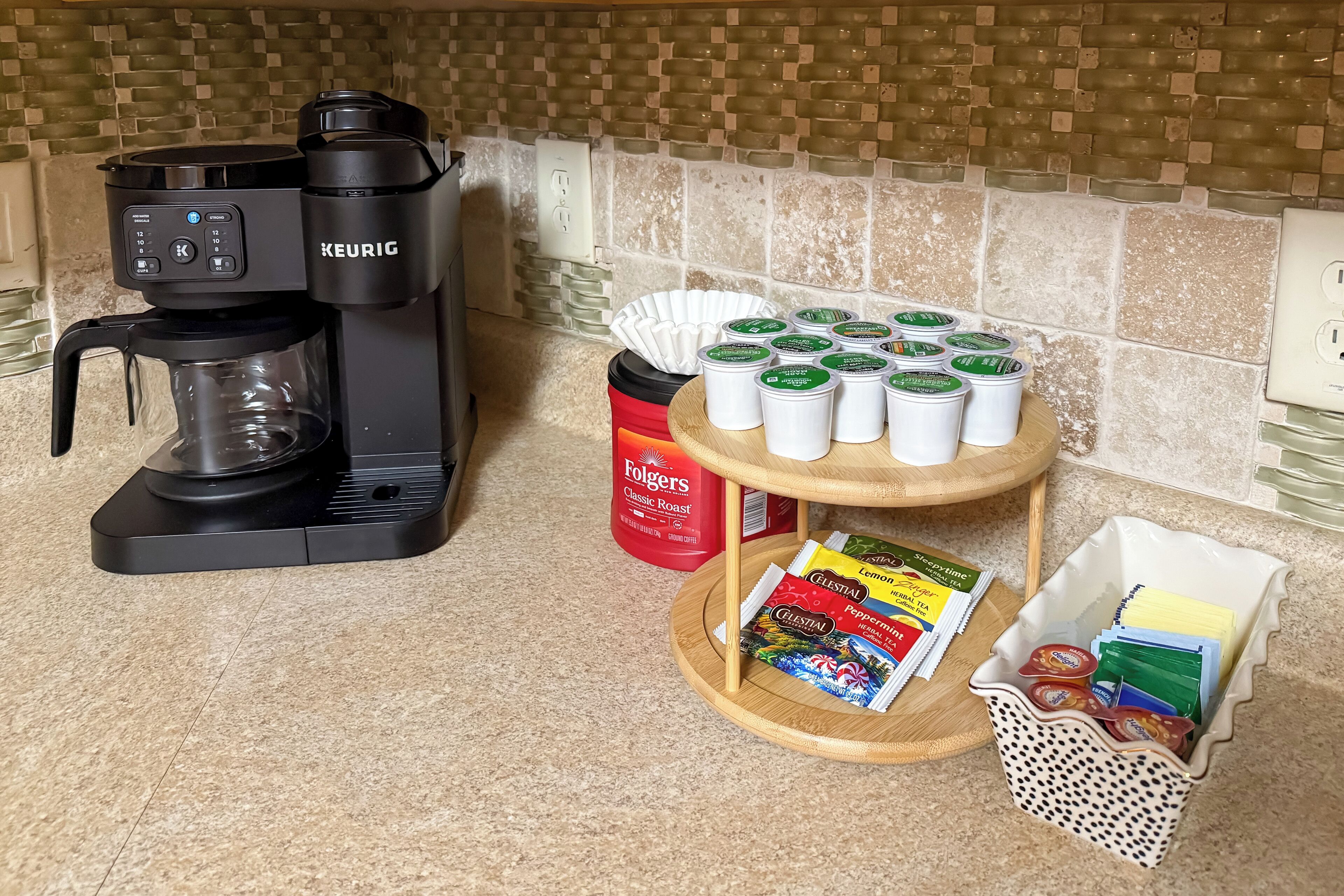 A kitchen with a Keurig coffee maker, Folgers coffee, and various coffee pods on a countertop.