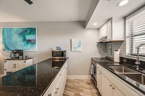 A modern kitchen with a granite countertop, stainless steel appliances, and artwork on the walls. - 2 Mi to Beach! Unit w/ Pool Access on Marco Island (Marco Island)